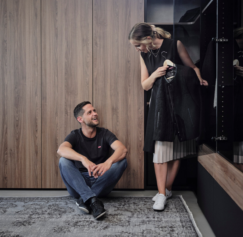 Kleiderschrank nach Maß mit offenen Elementen. Glückliches Paar steht davor.