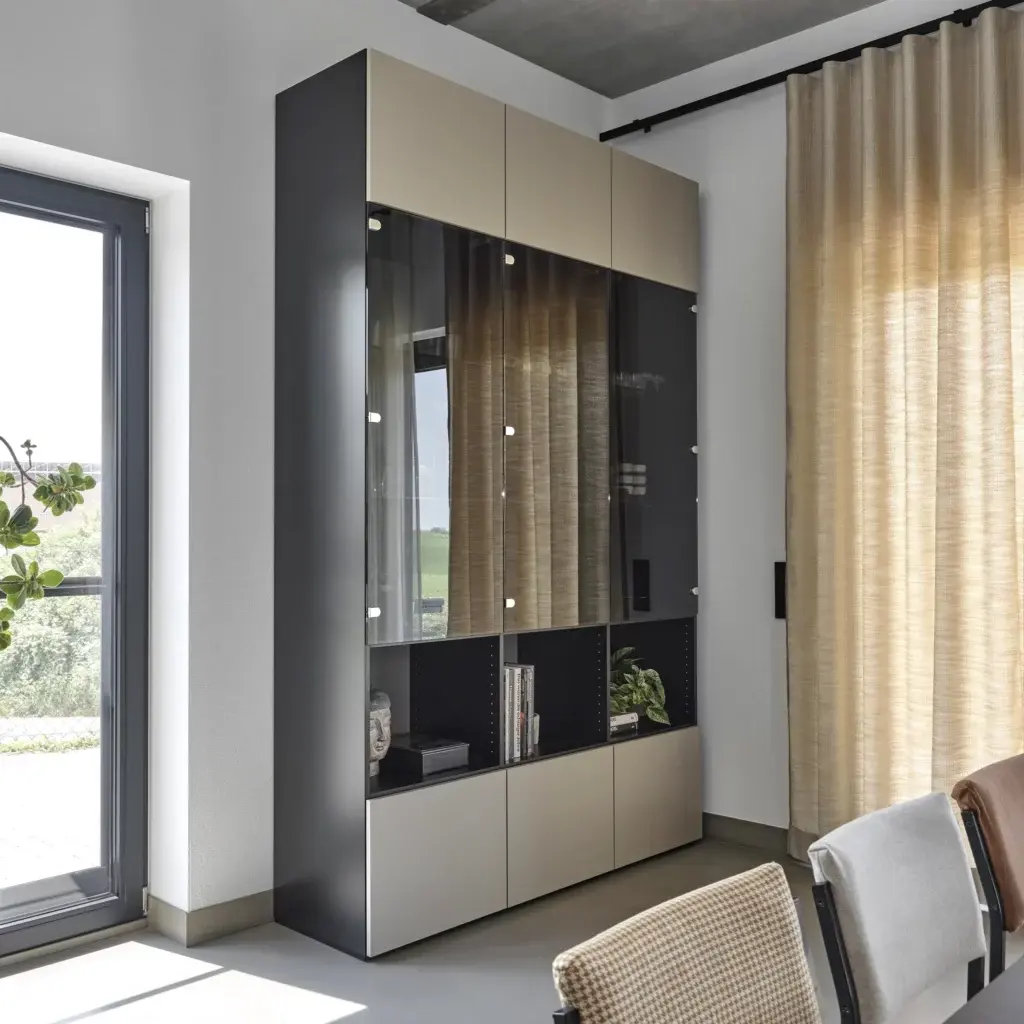 Deckenhohe Glasvitrine mit creme farbenen Fronten