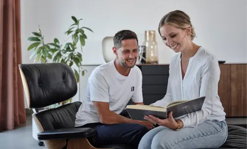 Glüchliches Paar sitzt vor einem Sideboard in einer schönen Wohnwelt