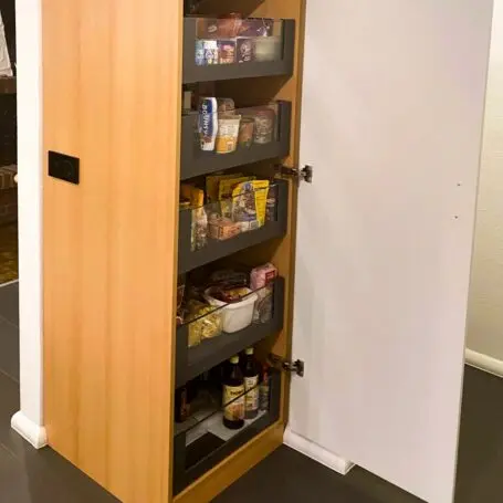 Brauner Apothekerschrank mit Auszuegen und weisser Tuer.